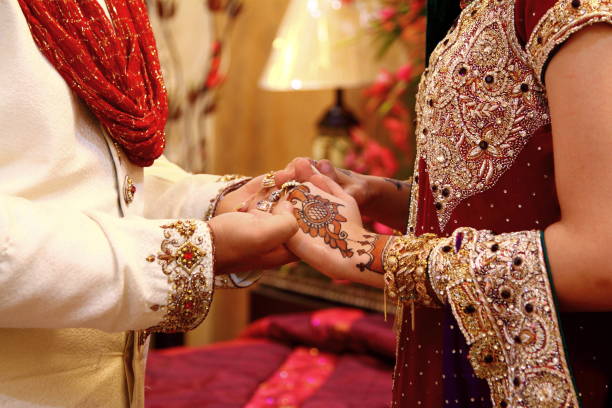 Bride and groom are holding their hands of each other, showing their love before starting a new married life. In Pakistan and India bride wear lots of jewelry in her hands and arms.